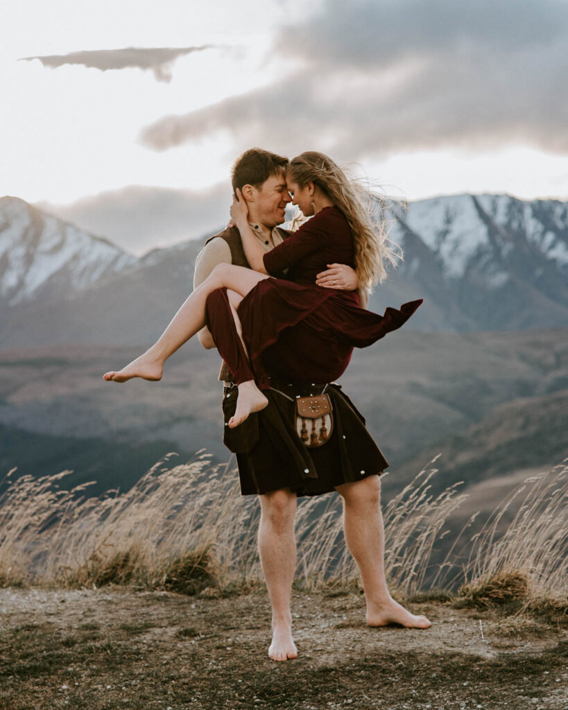 Husband holding wife with Ben Lomond and Queenstown in the background, as they renew their vows in New Zealand