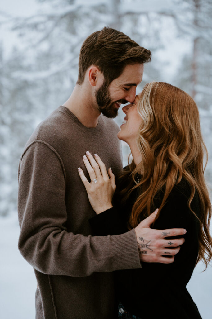 Surprise winter proposal inside a glass cabin in Äkäslompolo, Finland, photographed through the window during snowfall