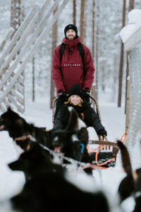 Newly engaged couple enjoying dog sledding during a winter engagement session in Finnish Lapland