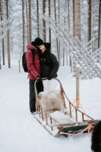Akaslompolo Finland Winter Engagement couple kissing on back of dog sled