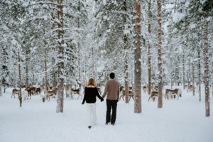 Akaslompolo Finland Winter Engagement couple walking towards wild reindeer