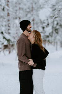 Akaslompolo Finland Winter Engagement couple laughing surrounded by wild reindeer