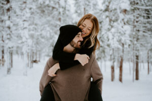 Akaslompolo Finland Winter Engagement snowy piggy back ride