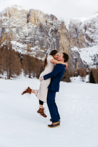 Passo Gardena Dolomites Winter Engagement, man picks up woman and the kiss