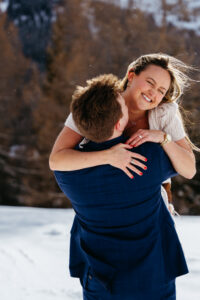 Passo Gardena Dolomites Winter Engagement, girl jumps onto man and they laugh