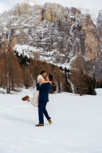 Passo Gardena Dolomites Winter Engagement, man swings girl around in the snow