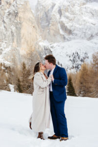 Passo Gardena Dolomites Winter Engagement, couple kisses and keep each other warm in the snow