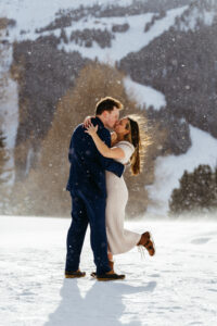 Passo Gardena Dolomites Winter Engagement, some bokeh snow while the engaged couple kisses