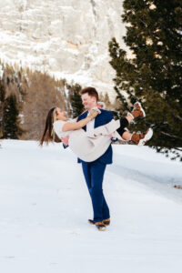 Passo Gardena Dolomites Winter Engagement, man picks up woman in the snow