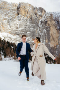 Passo Gardena Dolomites Winter Engagement, man and and woman running in snow
