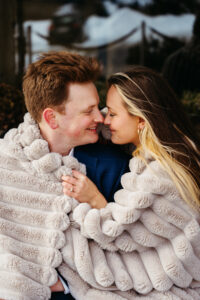 Passo Gardena Dolomites Winter Engagement, cute couple embracing with blanket