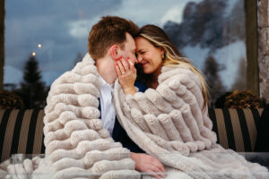 Passo Gardena Dolomites Winter Engagement, couple use cozy blanket to sit outside and keep warm