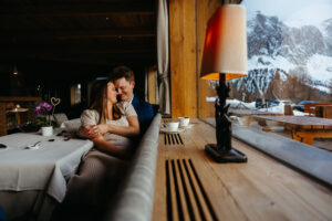 Passo Gardena Dolomites Winter Engagement, couple sharing hot chocolate to keep warm from the snow