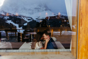 Passo Gardena Dolomites Winter Engagement, couple sharing a warm drink inside cozy hut