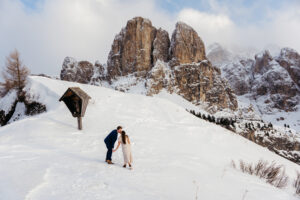 Passo Gardena Dolomites Winter Engagement, couple walking in the snow with the Odle range in the background