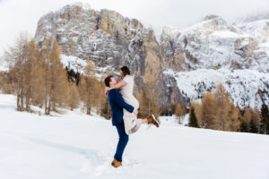 Passo Gardena Dolomites Winter Engagement, guy picks up girl and they smile in the snow