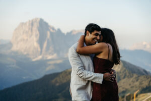 Seceda engagement session by helicopter in the Dolomites, man is smiling and woman is whispering in his ear