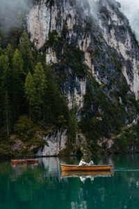 Engaged couple paddling across Pragser Wildsee during engagement at La Palifitta