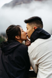 Asian couple kissing at Lago di Braies with moody skies