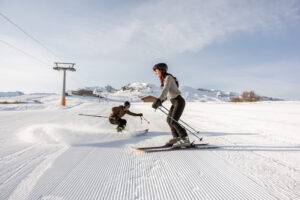 Man shredding pow during ski proposal with woman waiting to get snow on her