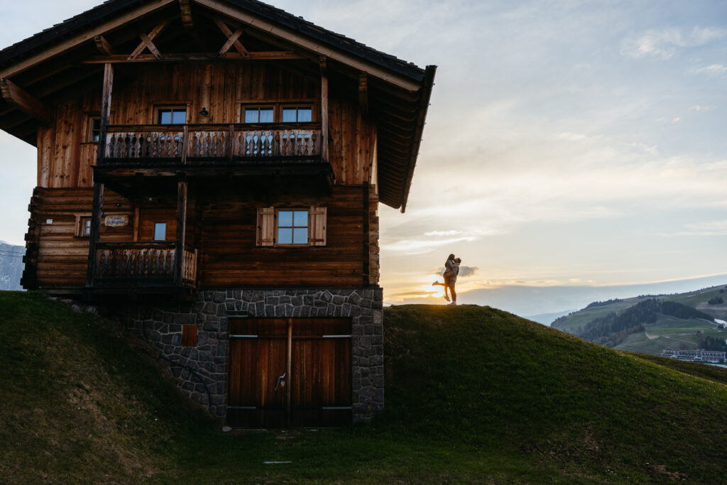 Cabin and man lifting up wife after he proposed to her in Seiser Alm in the Dolomites