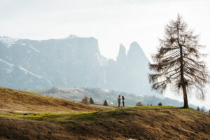 Man giving woman a ring just after they got engaged, with Dolomite mountains in the background on Seiser Alm