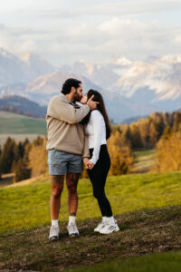 Man and woman kiss in activewear in the Dolomites after they got engaged