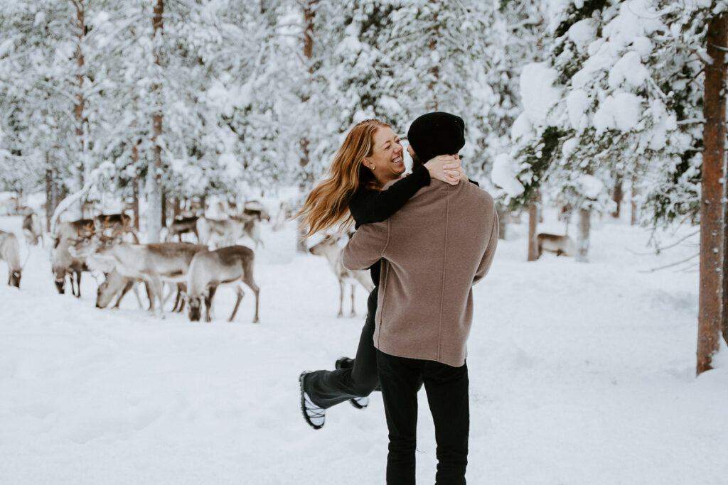 Man swinging his fiance around in winter snow in Akaslompolo with reindeer, one of the top 10 places to elope in Europe