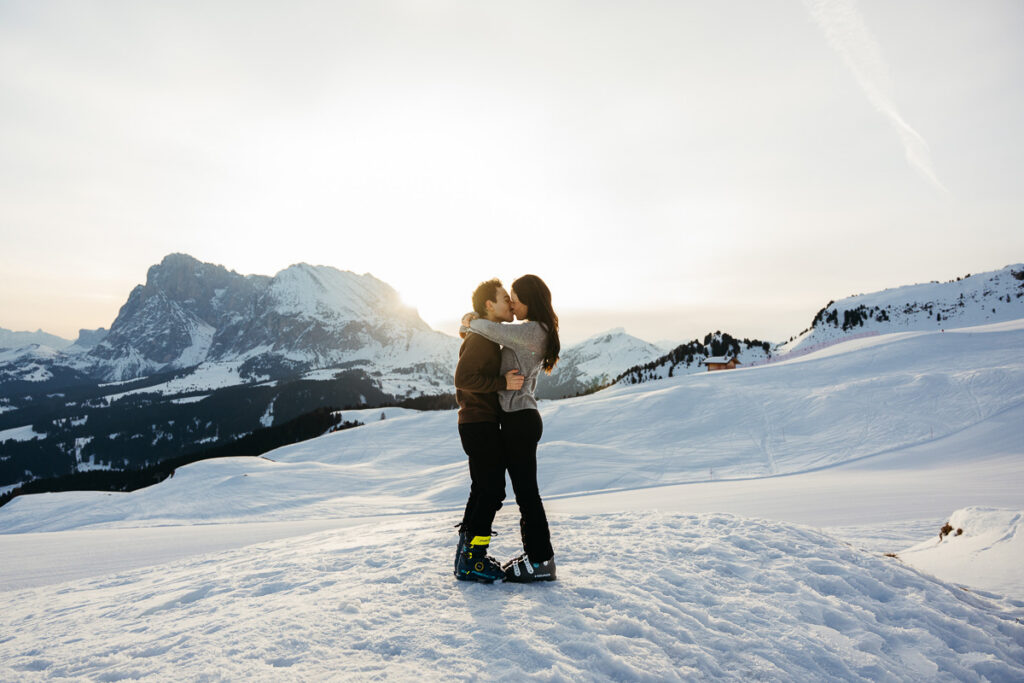 Newly engaged couple hugging as the sun rises over Langkofel and Platkofel in the Dolomites