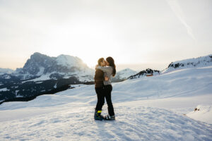 Newly engaged couple hugging as the sun rises over Langkofel and Platkofel in the Dolomites