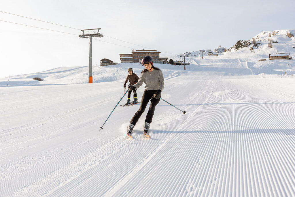 Newly engaged couple skiing down Alpe di Siusi