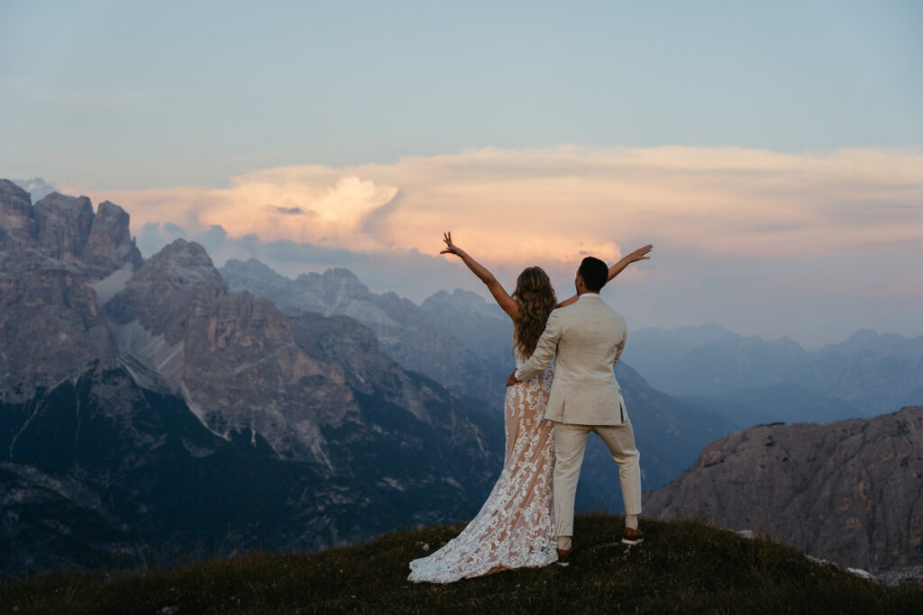 Bride and groom at sunset on Cadini di Misurina with orange clouds and mountains in the background