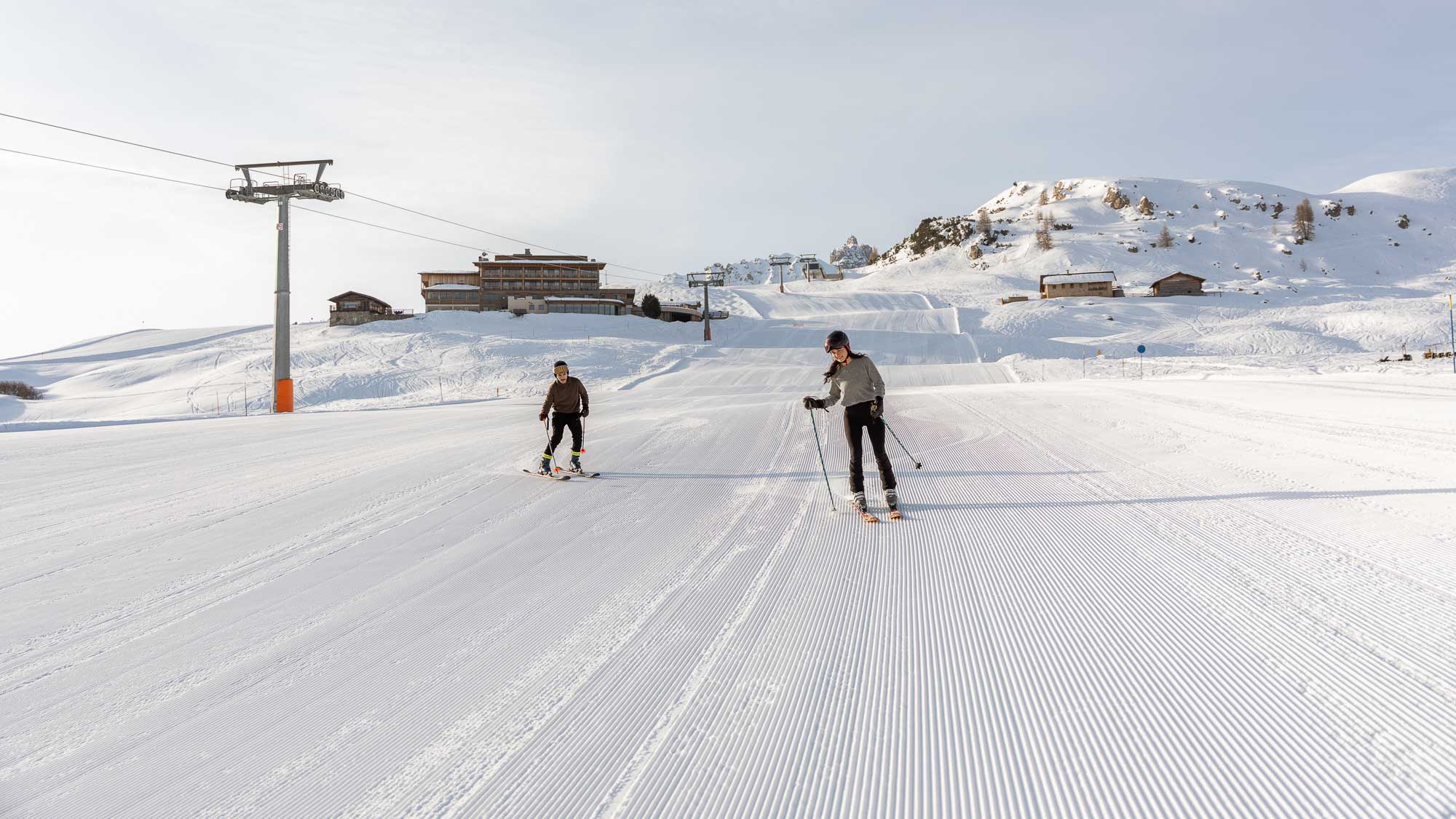 Newly engaged vegan couple skiing down Alpe di Siusi at sunrise on fresh tracks