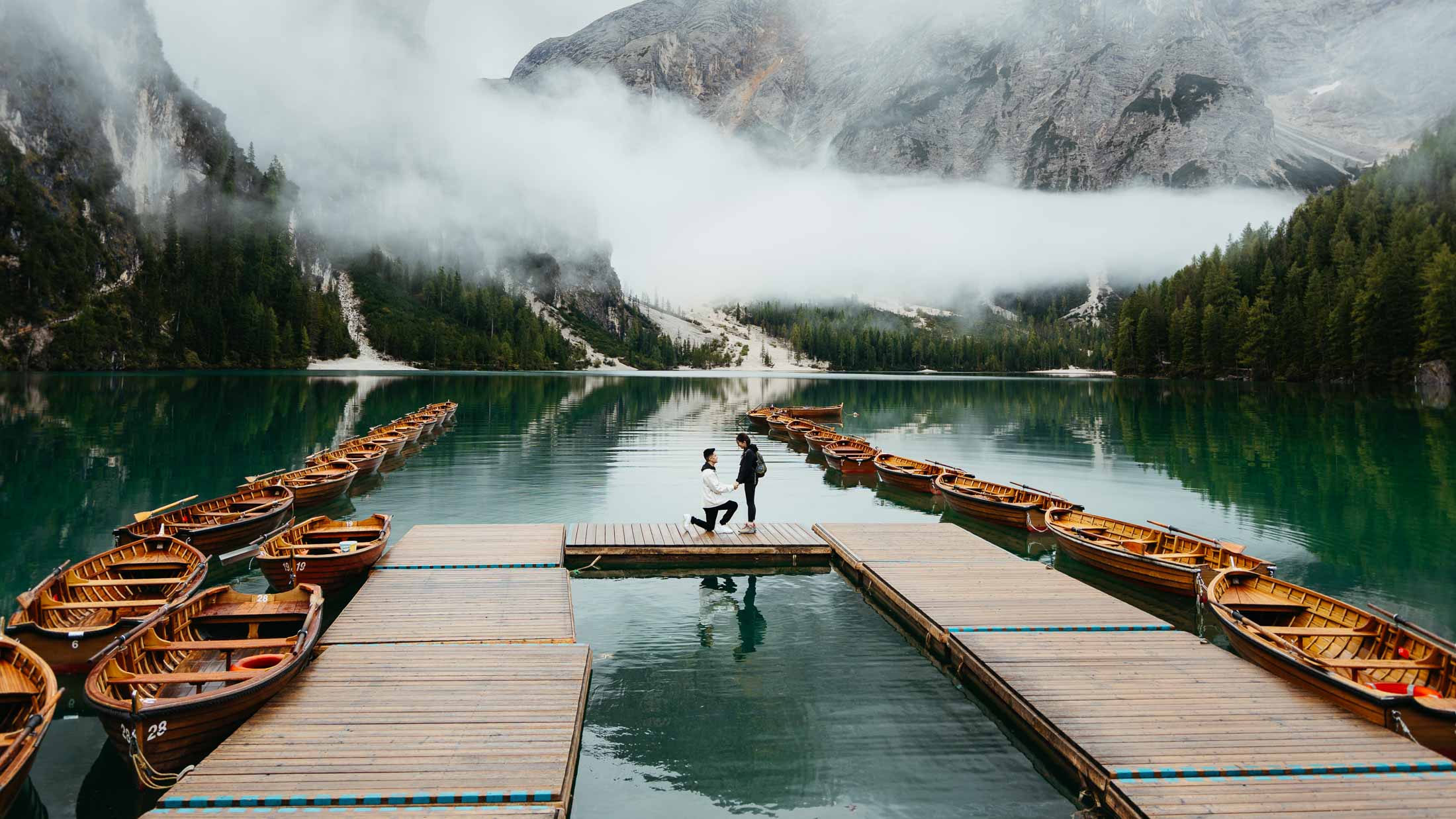 Man proposing to his girlfriend on Lake Braies with moody clouds everywhere