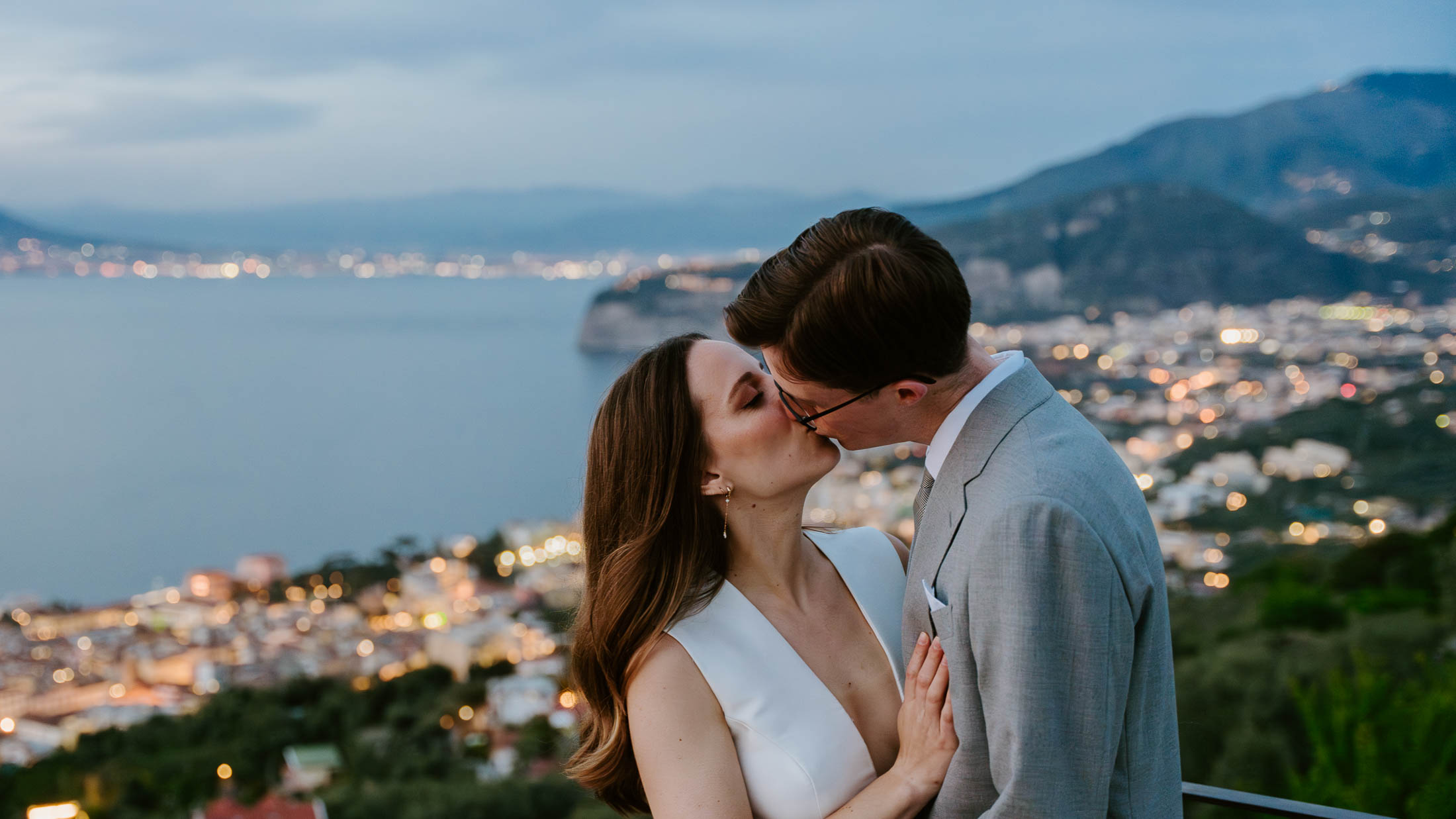 Bride and groom kissing with Sorrento lights in the background