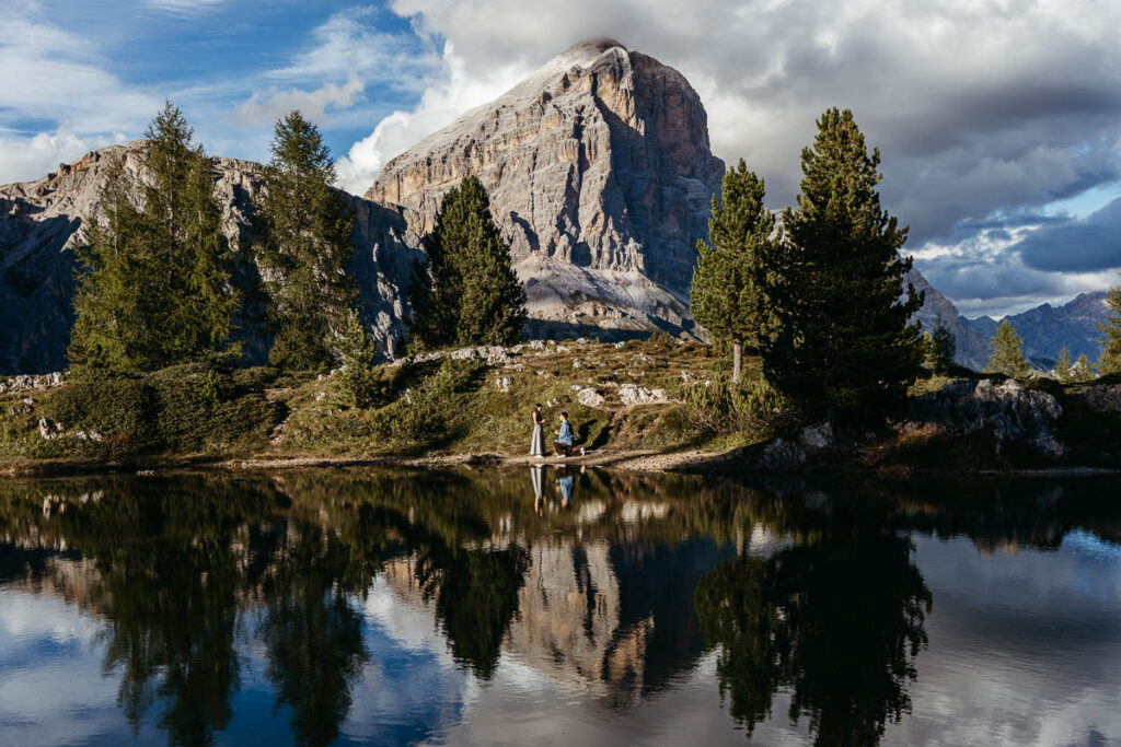 Man proposing to adventurous girlfriend on a hike in the Dolomites with lake reflections