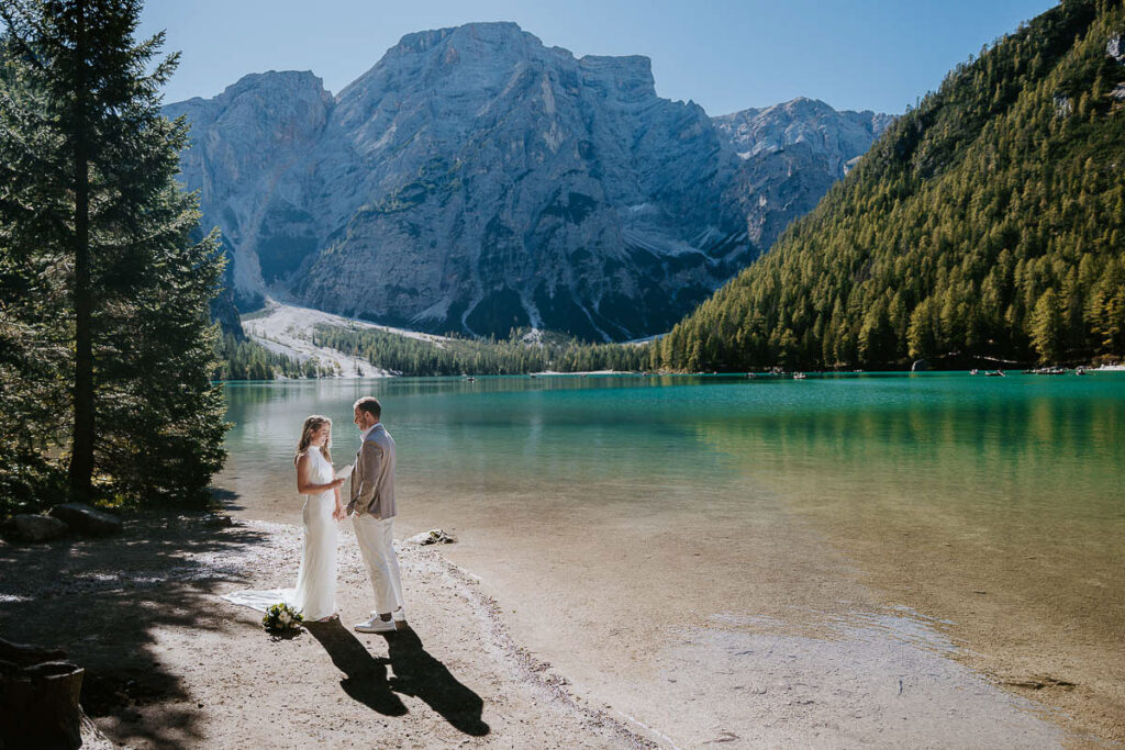 Sunny day at Lago di Braies with bride and groom eloping on the shore