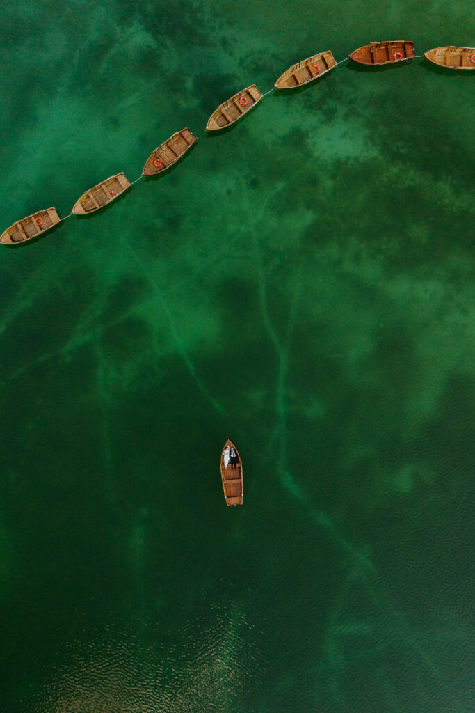 Drone view of bride and groom laying in the boat at Lago di Braies during their elopement
