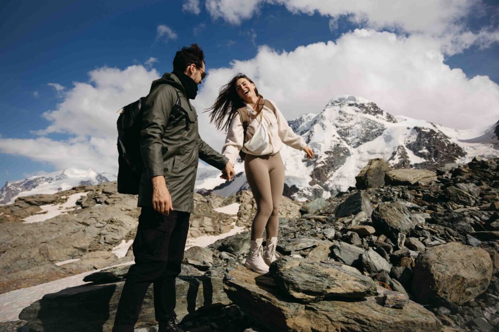 Bride and groom laughing as they stand on rocks on a hike in Switzerland; How to Elope in Switzerland