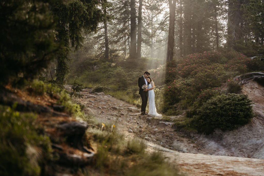 Light shining through forest onto bride and groom during their elopement in the Dolomites