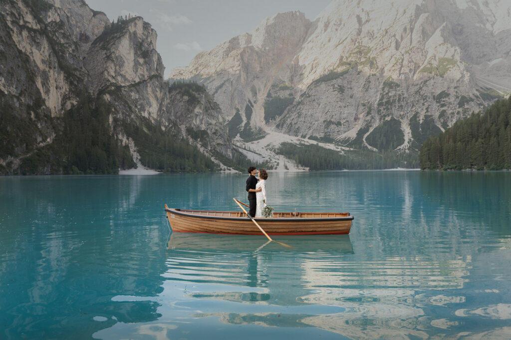 Bride and groom wearing ethical elopement outfits that were rented, while on a boat at Lago di Braies