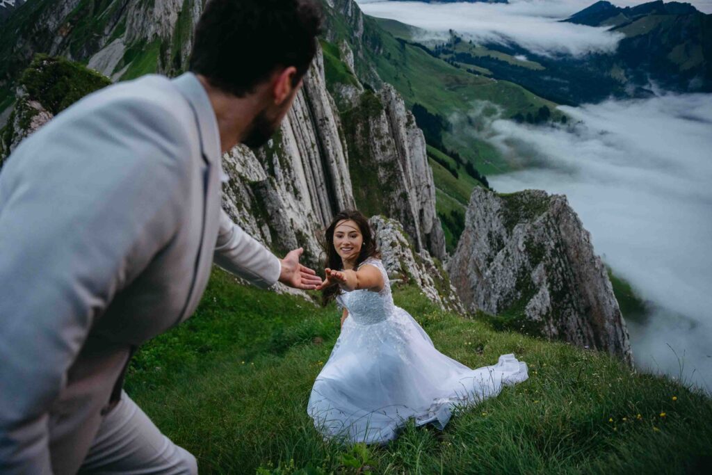 Bride reaching out for groom's hand in Swiss Alps during their elopement; How to Elope in Switzerland