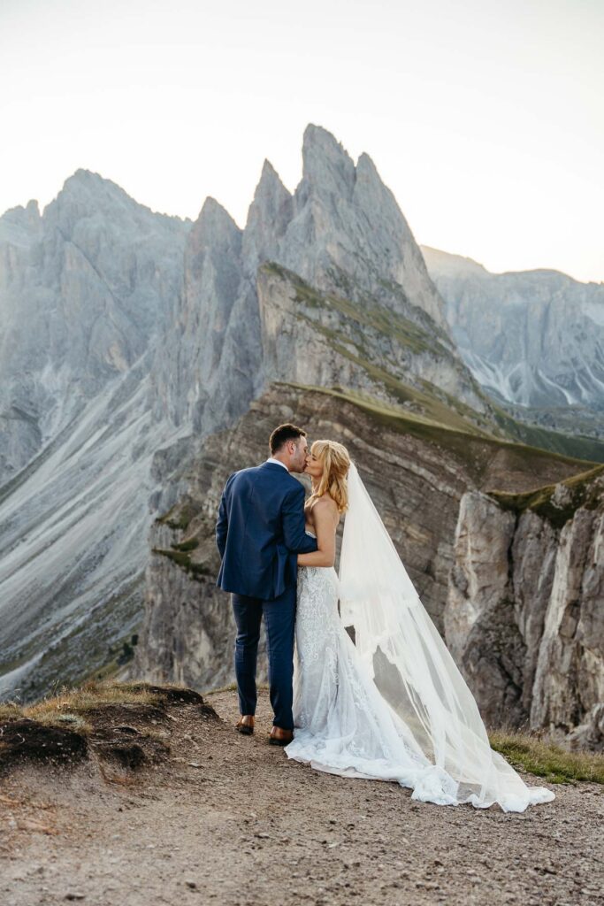 Bride and groom kissing with Seceda in the background
