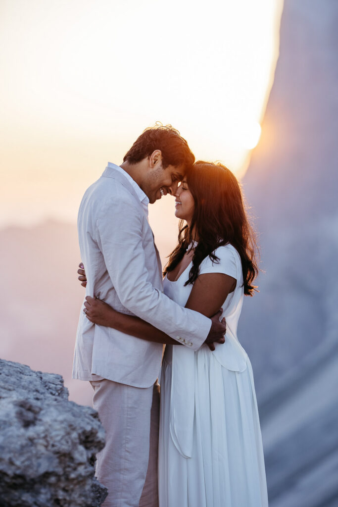 Newly engaged couple embracing as the sun starts to rise around Seceda