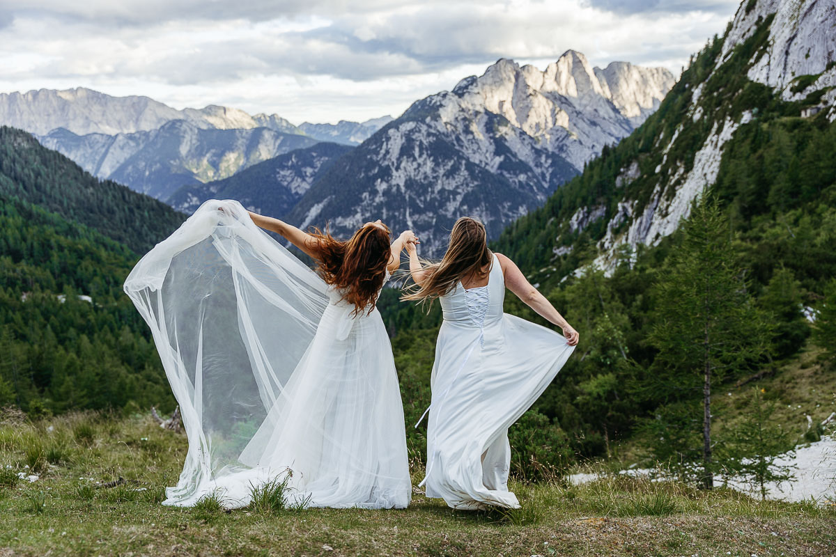 Two brides enjoying the breeze and letting the wind take their dresses away in Slovenia during their elopement