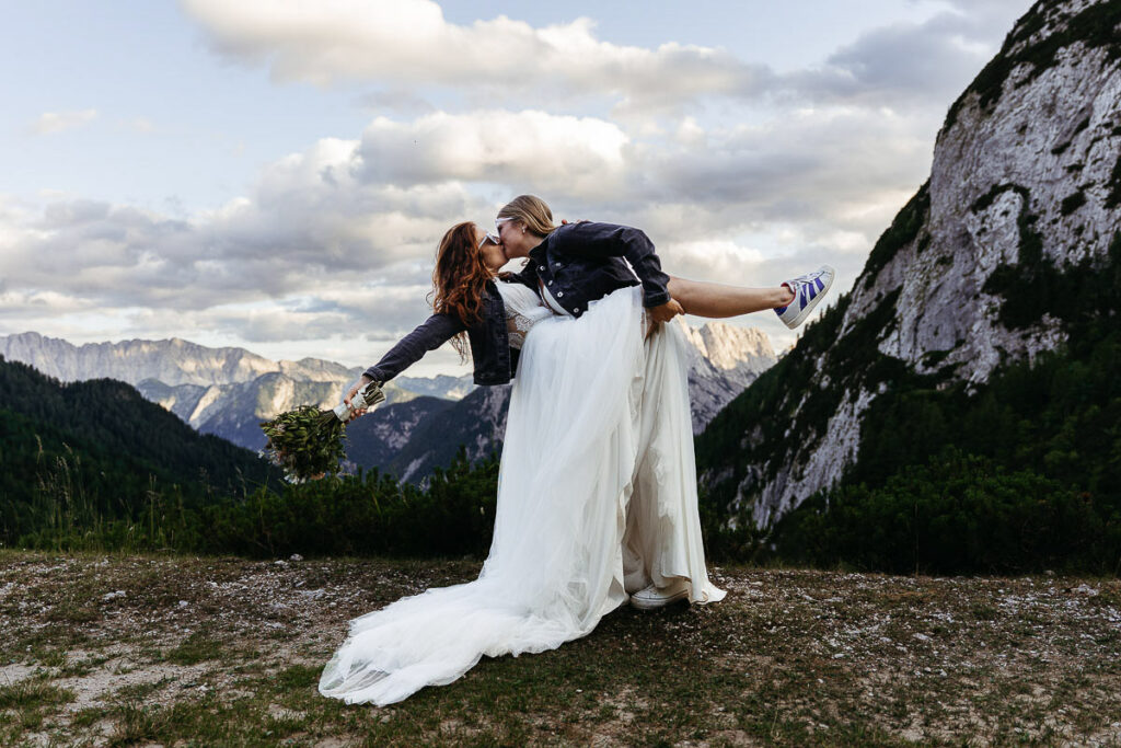 Brides cheering on their happy elopement, with Slovenian mountains in the background; Best Places to Elope on a Mountain in Europe