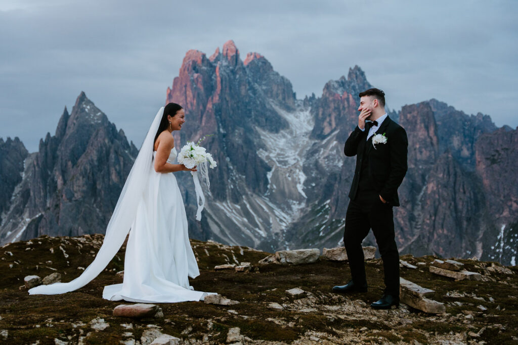 Bride and groom doing a first look with sunrise lighting up Cadini di Misurina