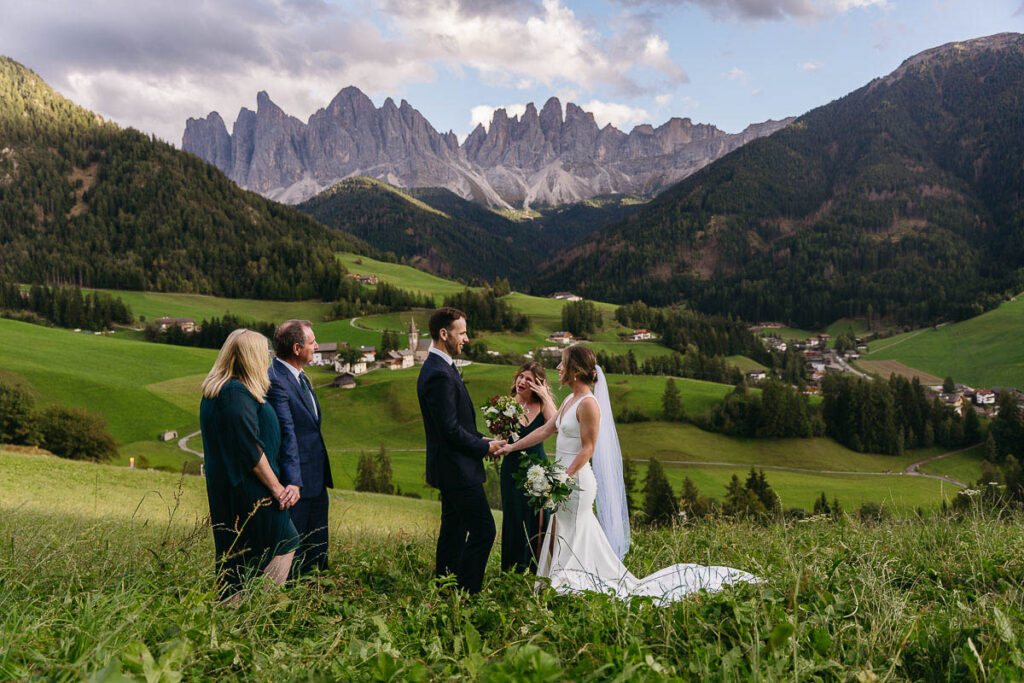 Bride, groom, and family during ceremony of eco-friendly wedding at Val di Funes in the Dolomites