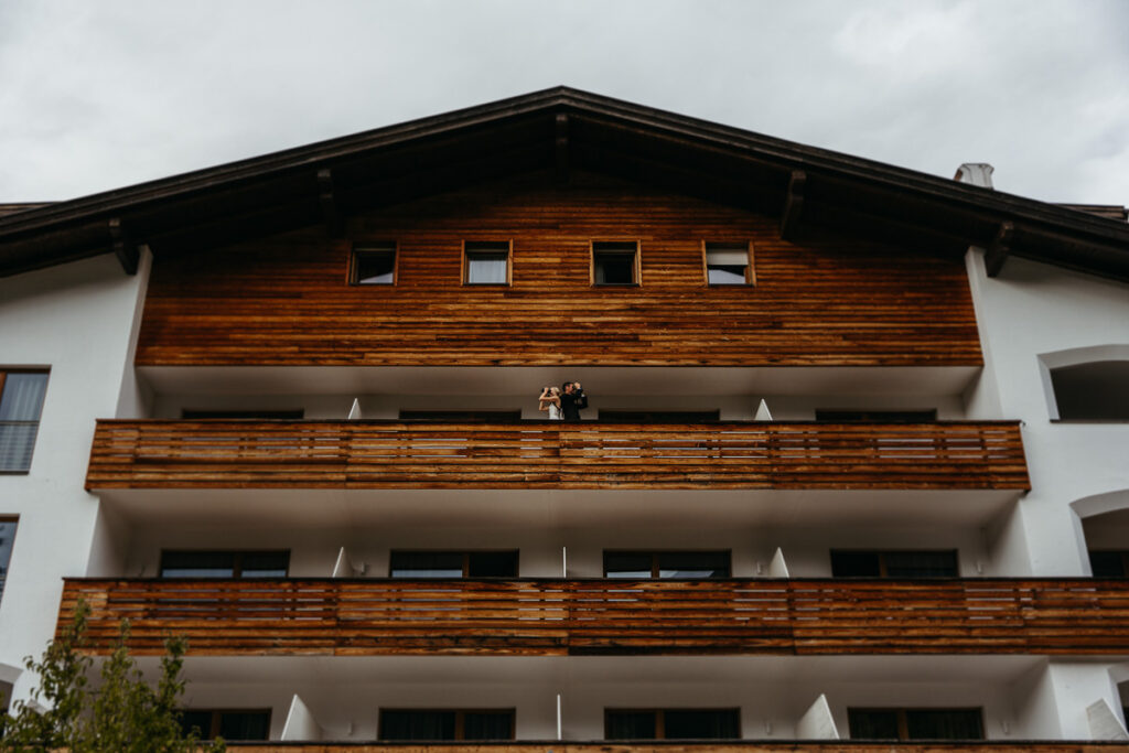 Bride and groom using binoculars for funny photo while standing on balcony at La Vimea vegan hotel