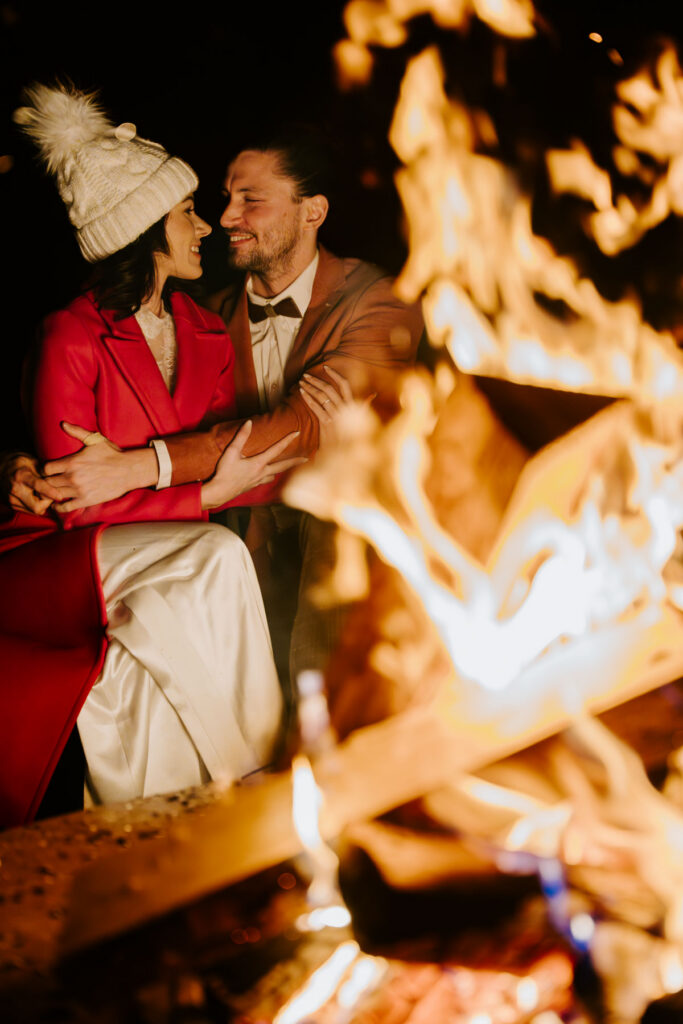 Well lit bonfire with bride and groom cozying up during their winter elopement at Vegan Paradiso Pure hotel in the Dolomites for their eco-friendly vegan wedding